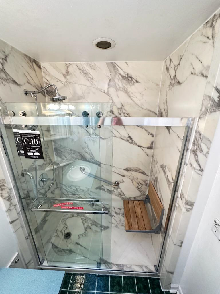 A bathroom with a marble shower stall and bench - bathroom remodeling and renovation from Oasis Bath Solutions of Kent Washington